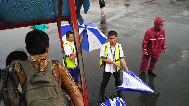 Saat mendarat cuaca sedang hujan, maka petugas bandara dengan sigap menyediakan payung untuk penumpang